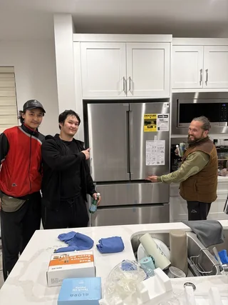 Three movers posing with a fridge delivery